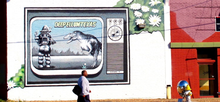 pedestrian walks by a mural in Deep Ellum, Dallas