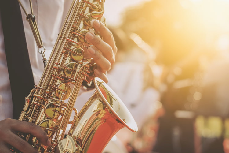 a man plays a saxophone at the deep ellum jazz festival during sunset