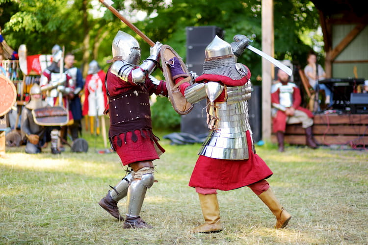 two scarborough renaissance festival visitors swordfight as other patrons watch