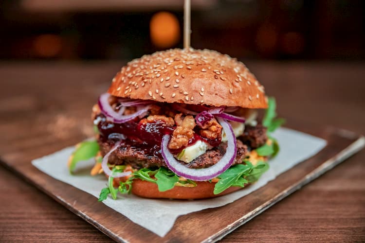 a burger with lettuce, red onions, and condiments held together with a toothpick at chelsea corner