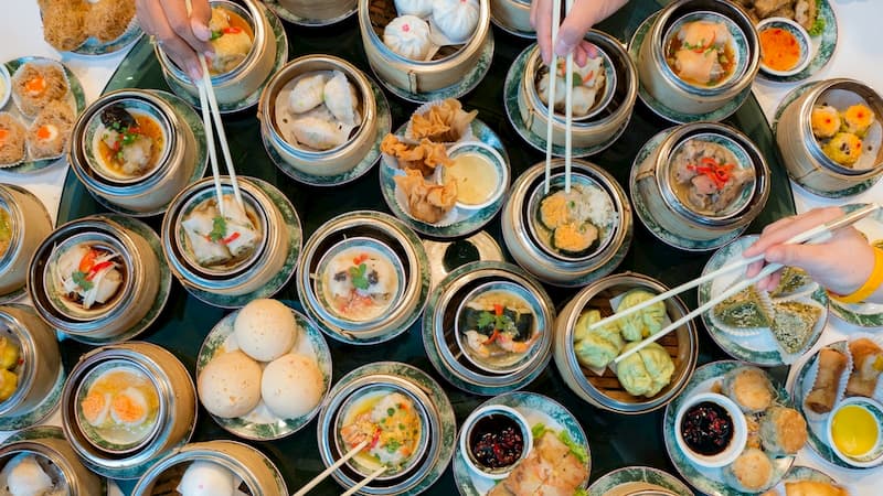 overhead view of a large table as friends share multiple plates of dim sum