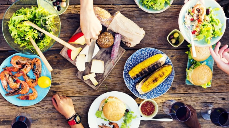 overhead view of a table as friends share a variety of different dishes in a food hall