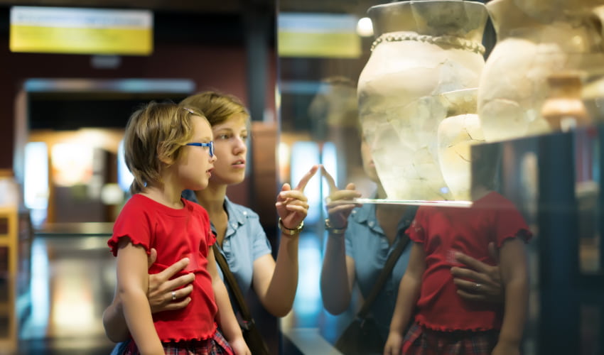 A woman and child examine an ancient vase in a history museum