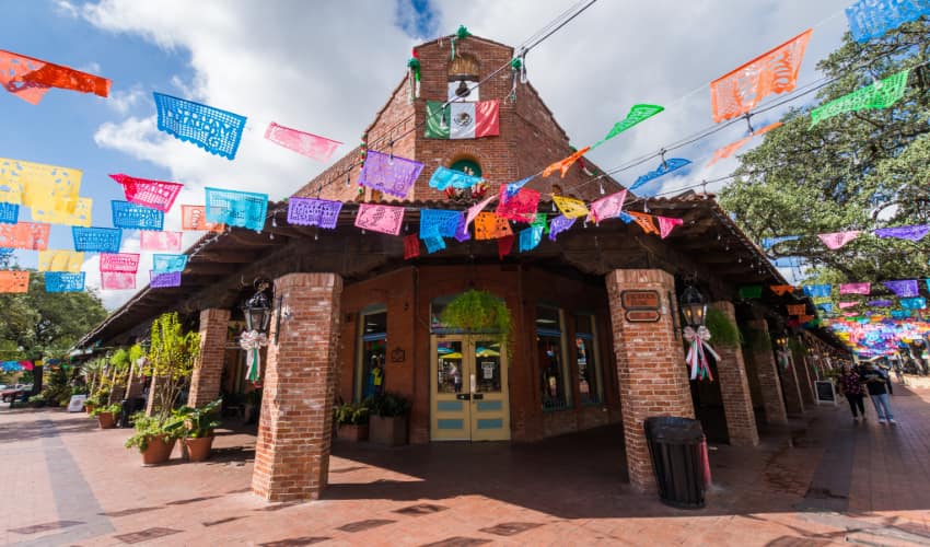 colorful paper decorations stream from an old brick building in the Historic Market Square in San Antonio