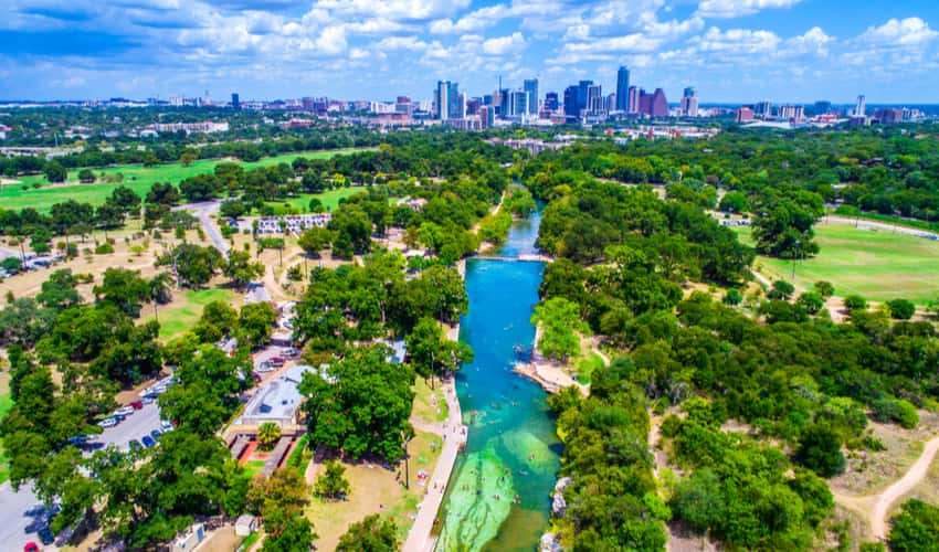 An aerial view of Barton Springs Pool and the Austin skyline 