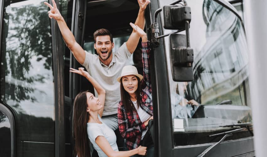 A group of smiling young people boarding a charter bus