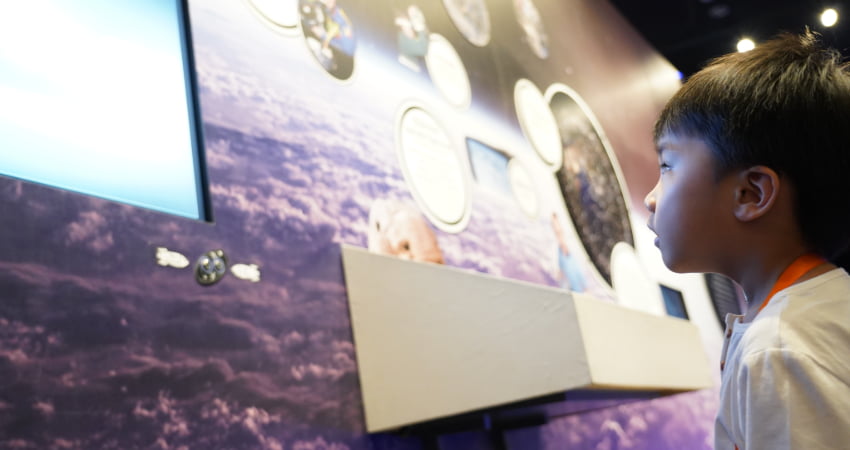 A child reads a sign about space exploration in a space museum