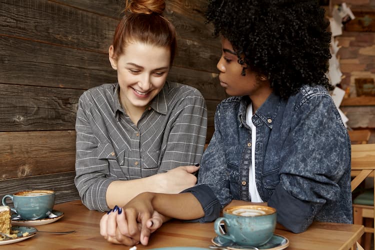 Two women holding hands at coffee shop