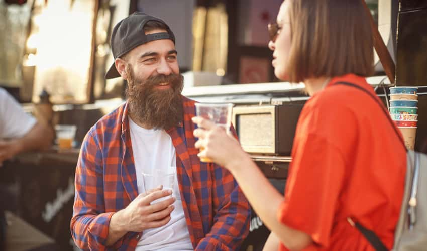 Two people drinking beer in front of a food truck