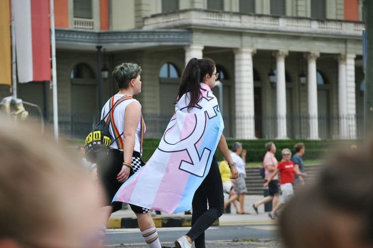 Woman wearing transgender flag walking with friend