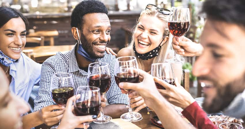 A group of friends toasting wine over a meal outside on a patio