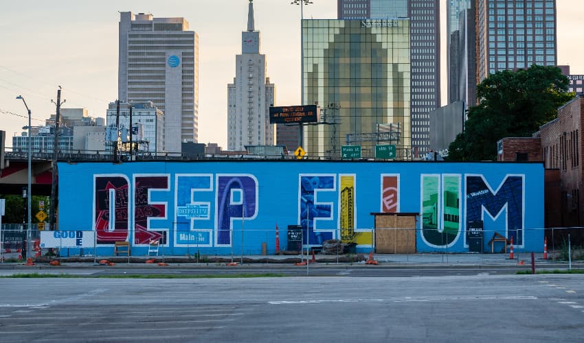 A mural on the side of a building reads "Deep Ellum" in bright letters