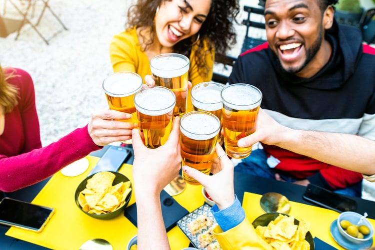 friends smile big and raise their beer glasses for a cheers