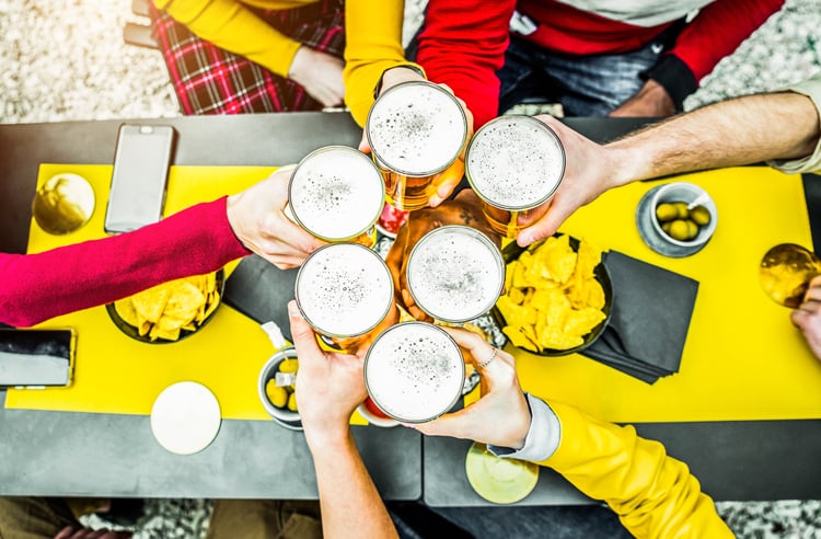 a top view of six friends clinking their beer glasses