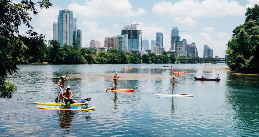 A group of friends paddleboard on a river outside Austin