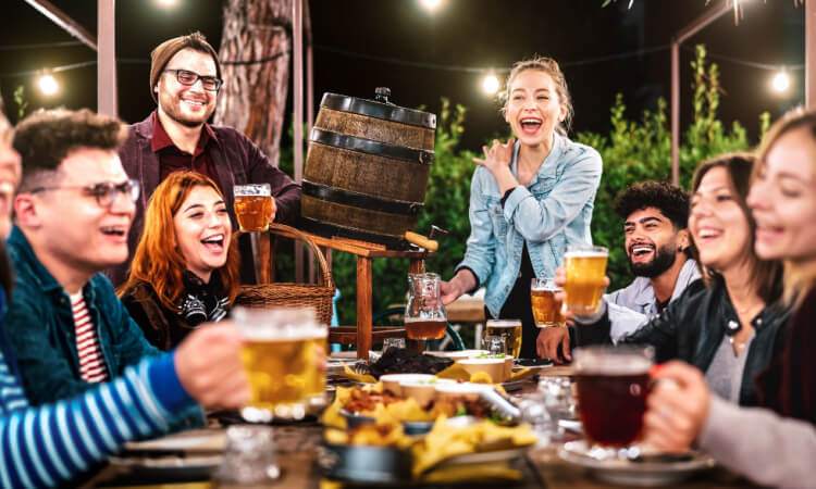 friends smiling and toasting beer in a biergarten at night