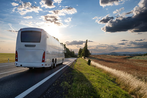 A white charter bus drives on a rural Dallas highway